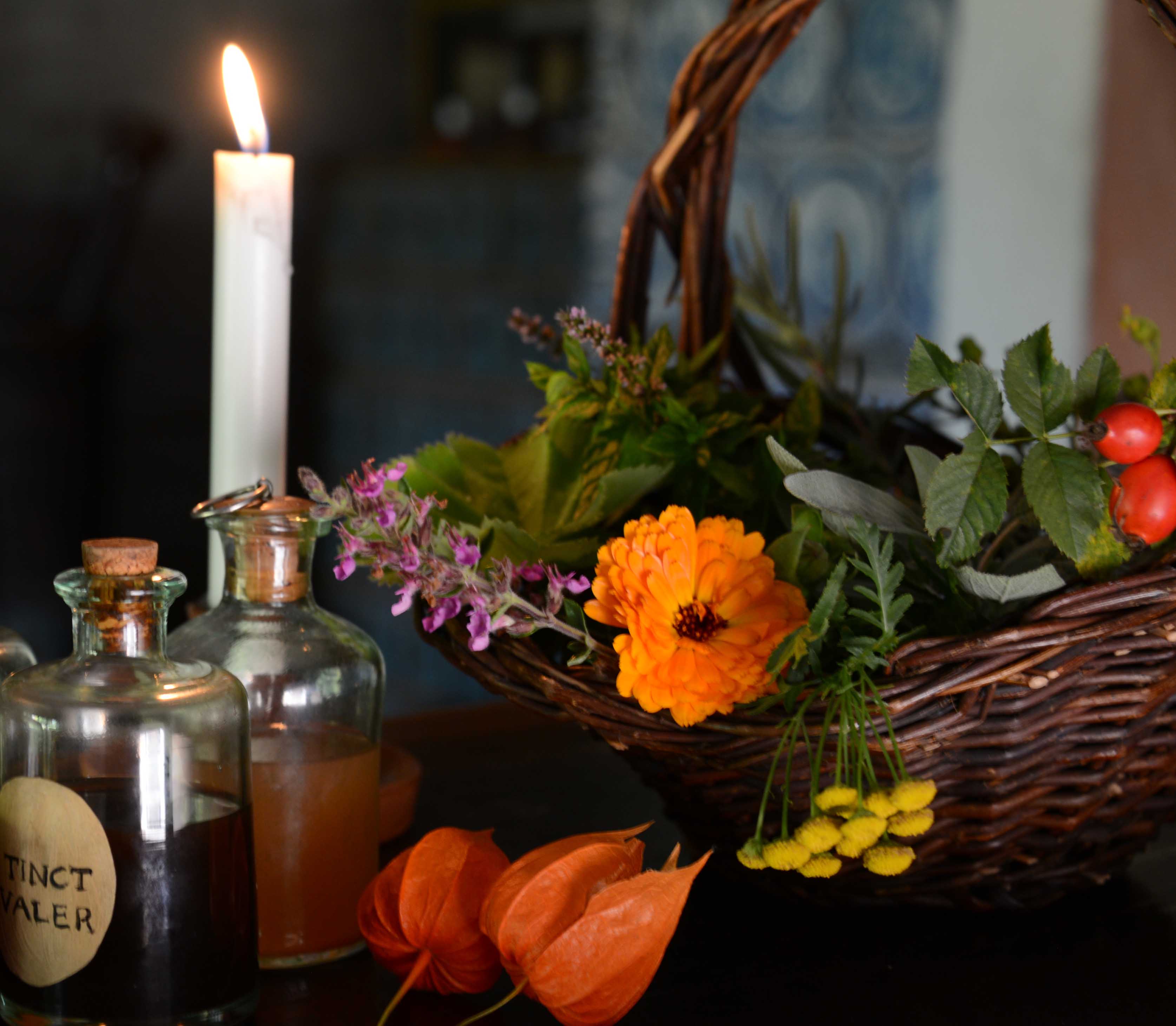 Bild från Skansens apotek. Korg med blommor, levande ljus och flaskor med tinkturer och botemedel.